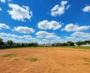 a dirt field with a blue sky with clouds at Terreno in São Pedro da Aldeia