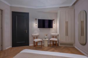 a bedroom with two chairs and a tv on the wall at Mountain Pine Luxury Suites in Florina