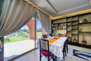 a dining room with a table and a large window at Villa Maloulou in Marrakesh