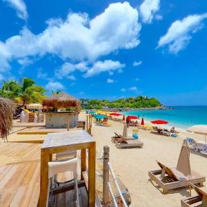 a beach with chairs and umbrellas and the ocean at Bora Bora Condo in Marigot