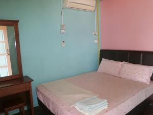 a bedroom with a bed with pink and blue walls at Rainbow Tioman Cottage in Kampong Juara