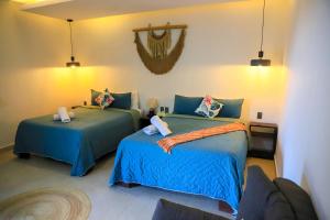 a bedroom with two beds with blue comforters at Hotel Diosa del Agua Bacalar in Bacalar