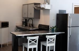 a kitchen with a black counter and two white stools at Fieldstone Guesthouse in Clearwater