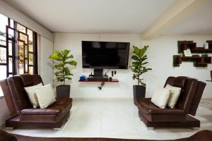 a living room with two chairs and a flat screen tv at Casa Lilí Guaduas in Guaduas