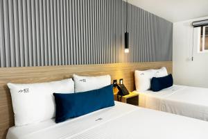two beds in a hotel room with blue and white pillows at Rest Inn Baja in Ensenada