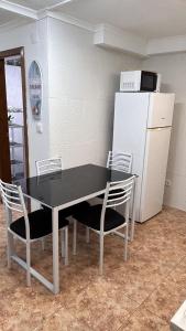 a kitchen with a black table and chairs and a refrigerator at Apartamento Caminho da Praia in Pedro Miguel