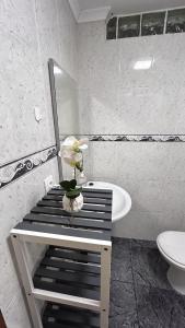 a bathroom with a sink and a table with a flower at Apartamento Caminho da Praia in Pedro Miguel +12 photos