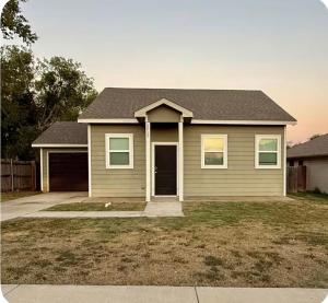 a brown house with a driveway and a house at Beautiful modern 3 bed 2 bath in Fort Worth