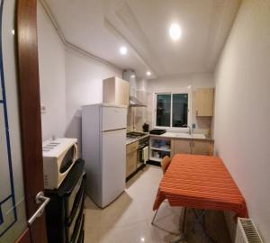 a small kitchen with a white refrigerator and a table at Luxe studio tunisia mall lac 2 in Tunis