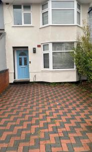 a house with a blue door and a brick driveway at Cozy 3 bed house in Coventry