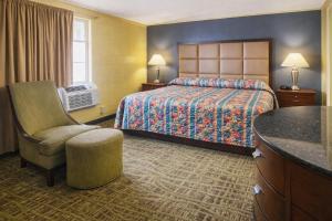 a hotel room with a bed and a chair at Bama Motel Mobile I-65 & US-90 in Mobile