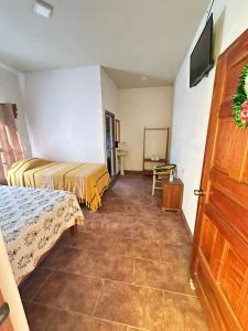 a room with two beds and a tv and a door at Hotel Hacienda Huasteca in Aquismón