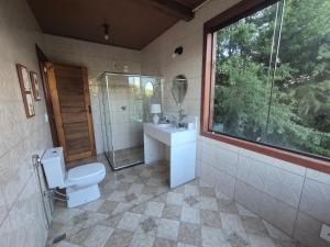 a bathroom with a toilet and a sink and a window at Pedra Azul Chalé Clássico in Domingos Martins