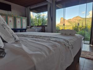 a bedroom with a large white bed with a large window at Pedra Azul Chalé Clássico in Domingos Martins