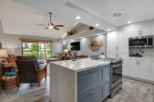 a kitchen with white cabinets and a living room at PL645 - Bay Hill Fairway - Alice Lodging in Palm Desert