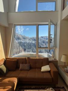 a living room with a couch in front of a large window at A63 Premium apartment located in hotel Vucko-private host in Jahorina