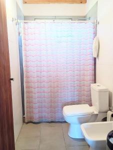 a bathroom with a shower curtain and a toilet at Village Pehuen in Balneario Pehuén-Có +9 photos