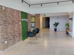 a lobby with two chairs and a brick wall at Apartamento Studio in Barbacena +39 photos