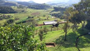 a view of a field with a house on a hill at Rancho Ca Fé - Casa Rural in Brazópolis +7 photos