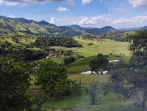 a view of a green field with trees and mountains at Rancho Ca Fé - Casa Rural in Brazópolis