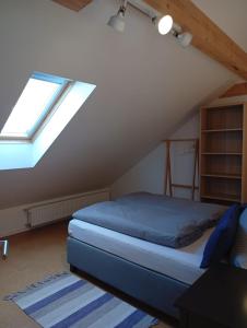 a attic bedroom with a bed and a window at Ferienhaus am Bach im Bayerischen Wald in Achslach