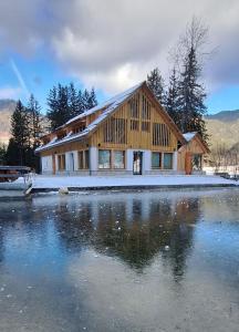 a large wooden house next to a body of water at Gostišče Jezersko in Zgornje Jezersko