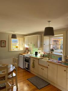 a kitchen with white cabinets and a table and a dining room at The Cottage Bailieborough Cavan in Bailieborough