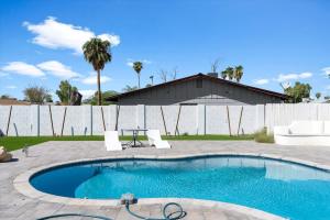 a swimming pool with a table and an umbrella at Rock and Glam Paradise in Mesa