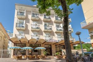 a hotel with tables and umbrellas in front of it at Hotel King in Rimini