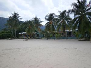 a resort on the beach with palm trees in the foreground at Rainbow Tioman Cottage in Kampong Juara