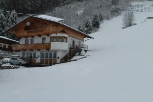 dom w śniegu przed górą w obiekcie Ferienwohnung Tummener w mieście Zell am Ziller