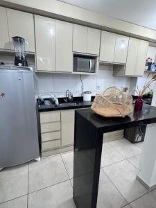 a kitchen with white cabinets and a black counter top at Apartamento 2 Quartos com Piscina e Garagem in Maceió