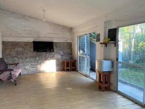 a living room with a stone wall and a tv at Casa con quincho en el Volcán in El Volcán