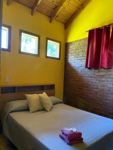 a bedroom with a bed with a brick wall and windows at Los Pinos in El Bolsón