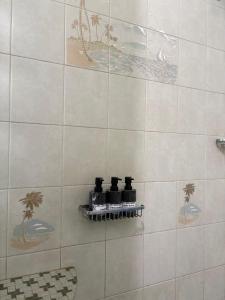 a white tiled shower with four bottles on a shelf at Bobby's Villa Beachfront, Paringao, La Union in Bauang +63 photos