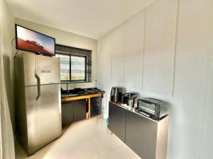 a small kitchen with a refrigerator and a microwave at Apartamento Pousada Essence Navegantes Praia Gravata in Navegantes +7 photos