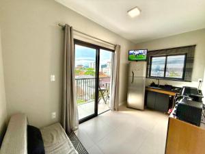 a living room with a sliding glass door to a balcony at Apartamento Pousada Essence Navegantes Praia Gravata in Navegantes