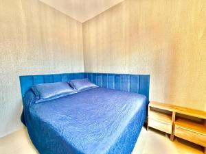 a bedroom with a blue bed in a room at Apartamento Pousada Essence Navegantes Praia Gravata in Navegantes