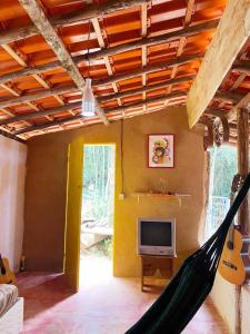 a hammock in a room with a tv and guitar at Canto da Águia in Ouro Preto