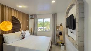 a bedroom with a large white bed and a tv at SilverLeaf in El Nido