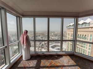 a woman standing in a room with large windows at Swissotel Al Maqam Makkah in Mecca