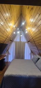 a bed in a room with a wooden ceiling at chalé dos Buritis 01 in Chapada dos Guimarães +5 photos