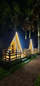 a wooden cabin with a fence and palm trees at night at chalé dos Buritis 01 in Chapada dos Guimarães