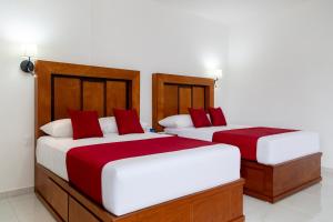 two beds in a room with red and white at Hotel alcazar de luna in Chilpancingo de los Bravos