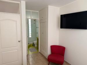 a room with a red chair and a tv on a wall at Huacachina Boutique Hotel in Ica