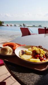 a plate of breakfast food on a table with the beach at GoldMen Vila do Mar Natal in Natal