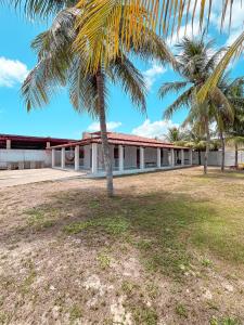 a building with palm trees in front of it at Casa Mar e Rio Milagres in São Miguel dos Milagres