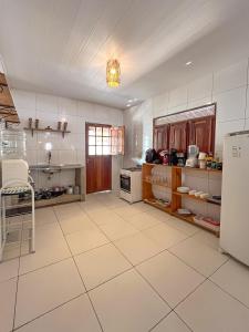 a large kitchen with white tile floors and a refrigerator at Casa Mar e Rio Milagres in São Miguel dos Milagres +12 photos