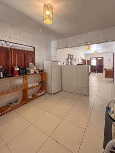 a large kitchen with a refrigerator and a tiled floor at Casa Mar e Rio Milagres in São Miguel dos Milagres