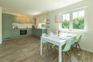 a kitchen and dining room with a white table and chairs at Ferienhaus-Belvedere-2-c in Blekendorf